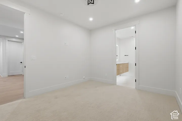 Neutral interior room featuring plush carpeting, recessed lighting, and solid-core interior doors with matte black hardware