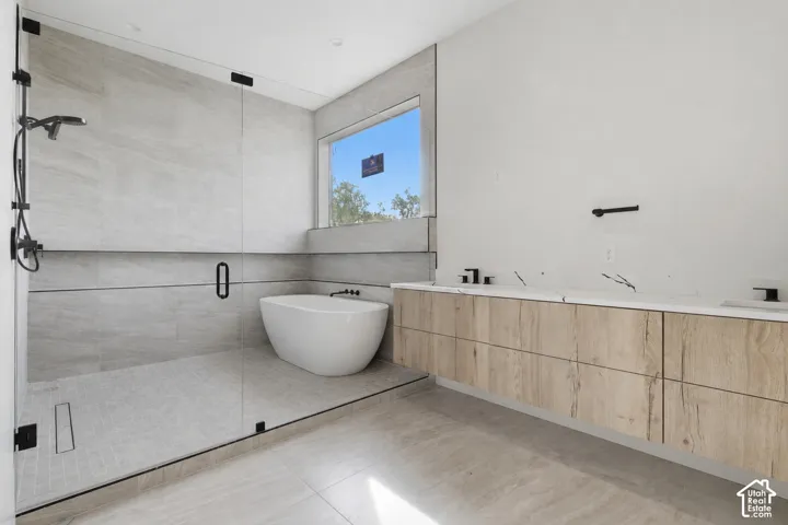 Spacious wet room featuring a freestanding tub, glass-enclosed shower, and a long floating vanity with wood-finish cabinetry and a light-toned countertop