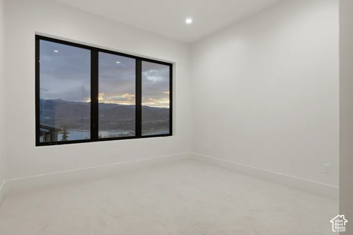 Interior space featuring neutral wall tones, plush wall-to-wall carpeting, recessed ceiling lighting, and large windows with black frames highlighting mountainous terrain