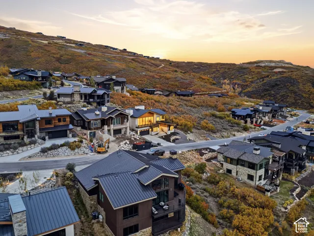 Aerial perspective featuring multi-level mountain residences with metal roofing, stone masonry accents, wood siding, and expansive natural landscape
