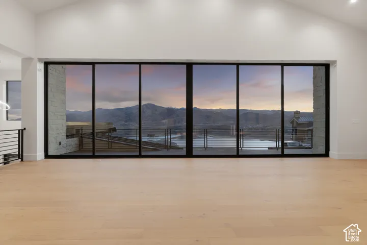 Expansive interior space featuring vaulted ceilings, light-toned wood-finish flooring, and floor-to-ceiling multi-panel sliding glass doors