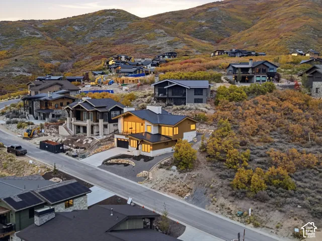 Multi-level architectural design featuring expansive floor-to-ceiling windows, metal roofing, composite siding, and an attached two-car garage set against a mountainous landscape