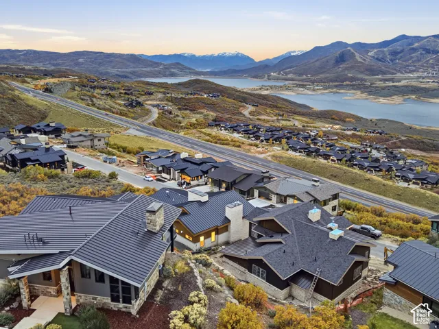 Contemporary residence featuring metal roof architecture, stone masonry siding, prominent stone chimneys, and expansive reservoir and mountain scenery