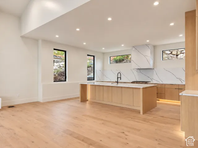 Spacious kitchen with a light wood-finish island, white countertop, and integrated sink with a black faucet