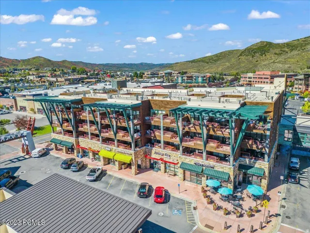 Multi-story commercial building featuring multiple balconies, ground-level retail spaces with awnings, and an outdoor patio area