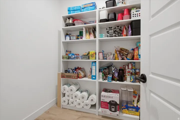 White built-in shelving with multiple storage levels, a white paneled door with a black handle, and light wood-finish flooring