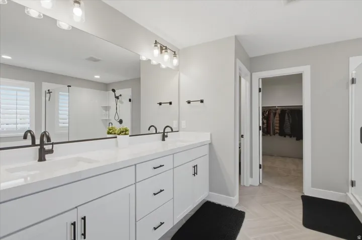 Double vanity with white cabinetry, matte black hardware, and an expansive mirror