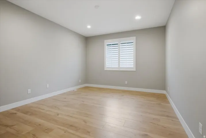 Wood-finish flooring, recessed lighting, and a window with white plantation shutters