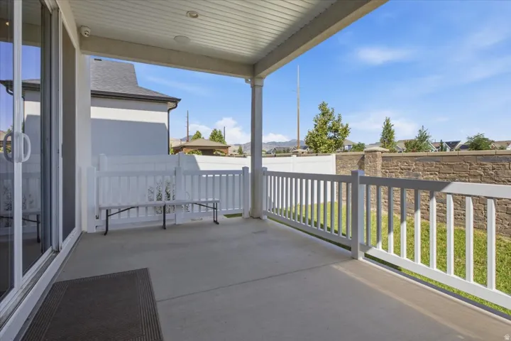 Covered concrete patio featuring white railing and column