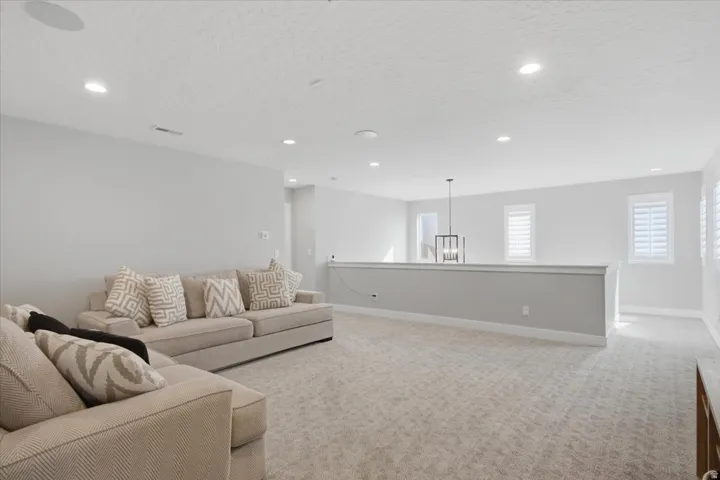 Carpeted floor with recessed lighting and a decorative pendant light fixture