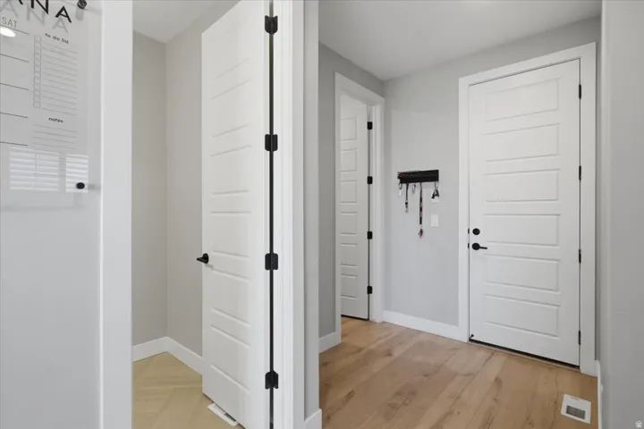 Wood-finish flooring, white paneled doors with matte black hardware, and light gray wall finishes