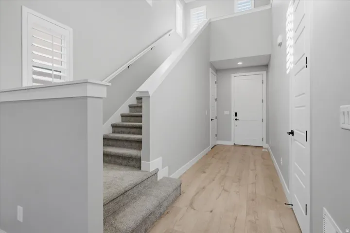 Entryway featuring wood-finish flooring, a carpeted staircase, and white interior doors with black hardware