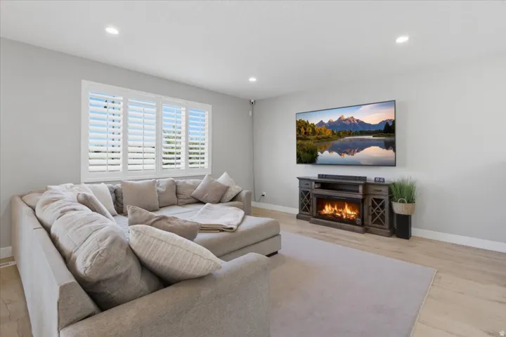 Recessed lighting, window with plantation shutters, wood-finish flooring, and built-in electric fireplace