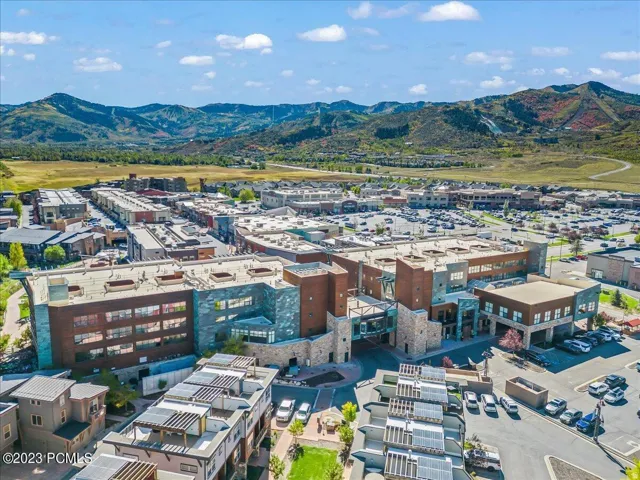 Expansive development featuring a mix of commercial and residential buildings, prominent mountain scenery, and solar panels on various rooftops