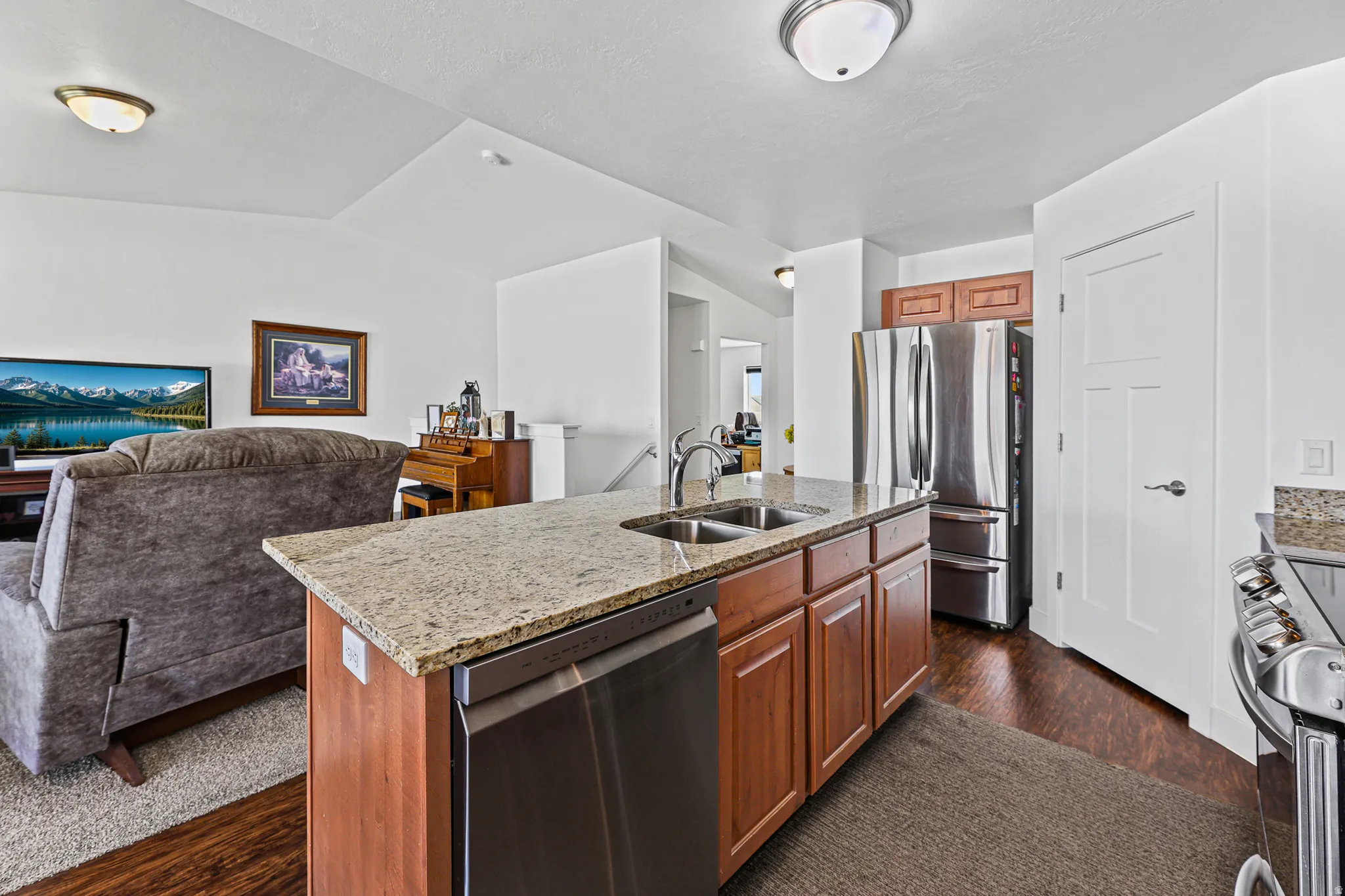 Kitchen island with a granite countertop, undermount sink, and integrated dishwasher