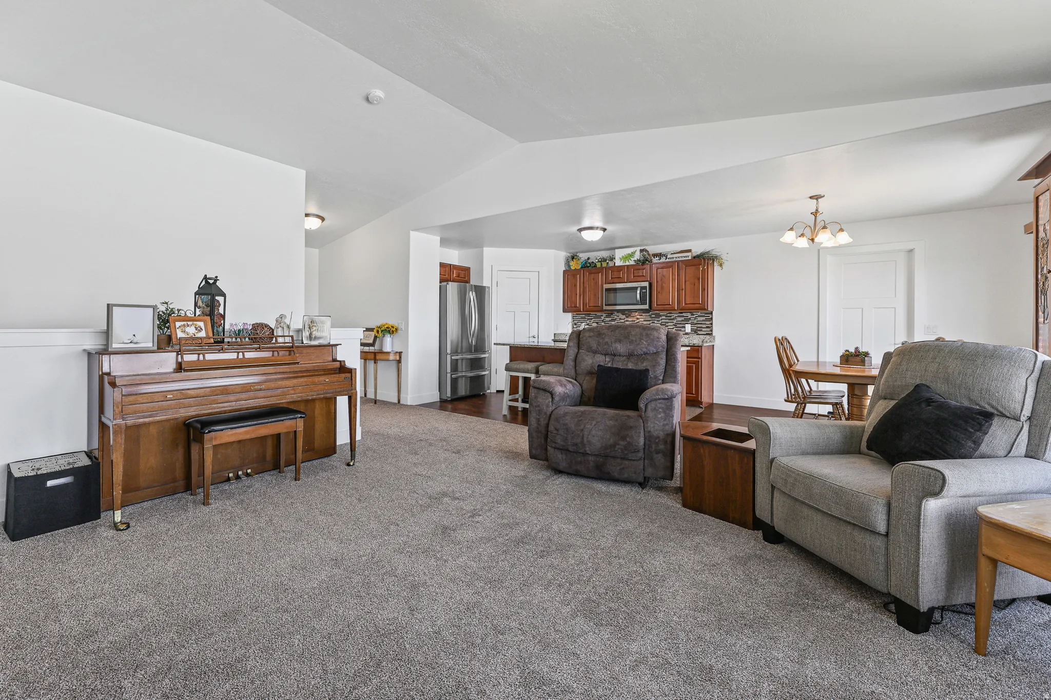 Open-concept living area featuring light gray carpeting and white walls