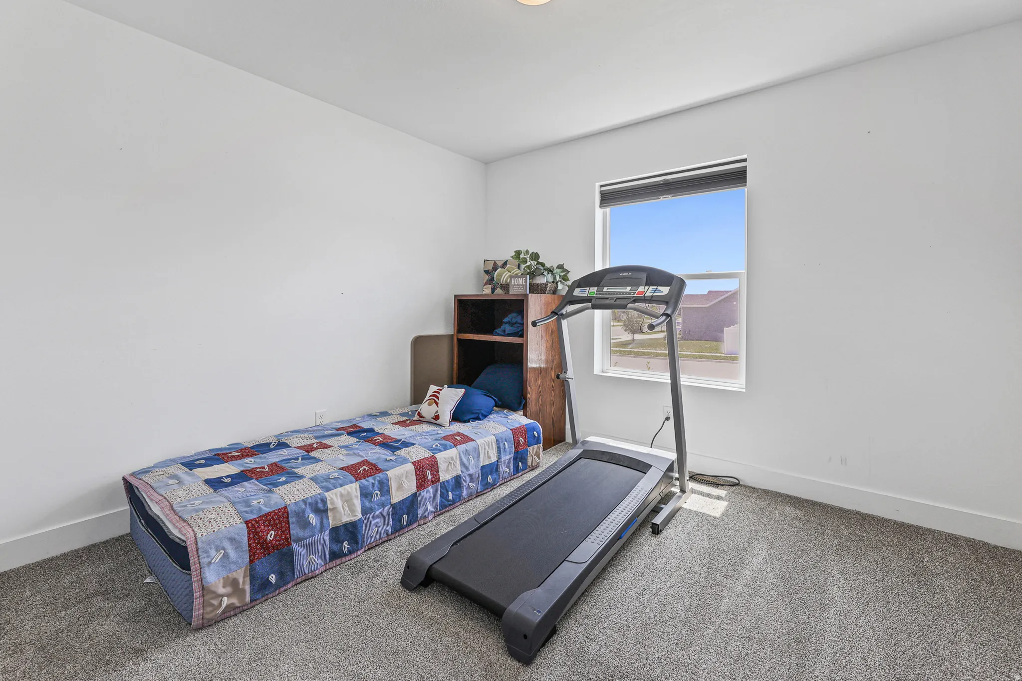 Carpeted room with a single window and white walls