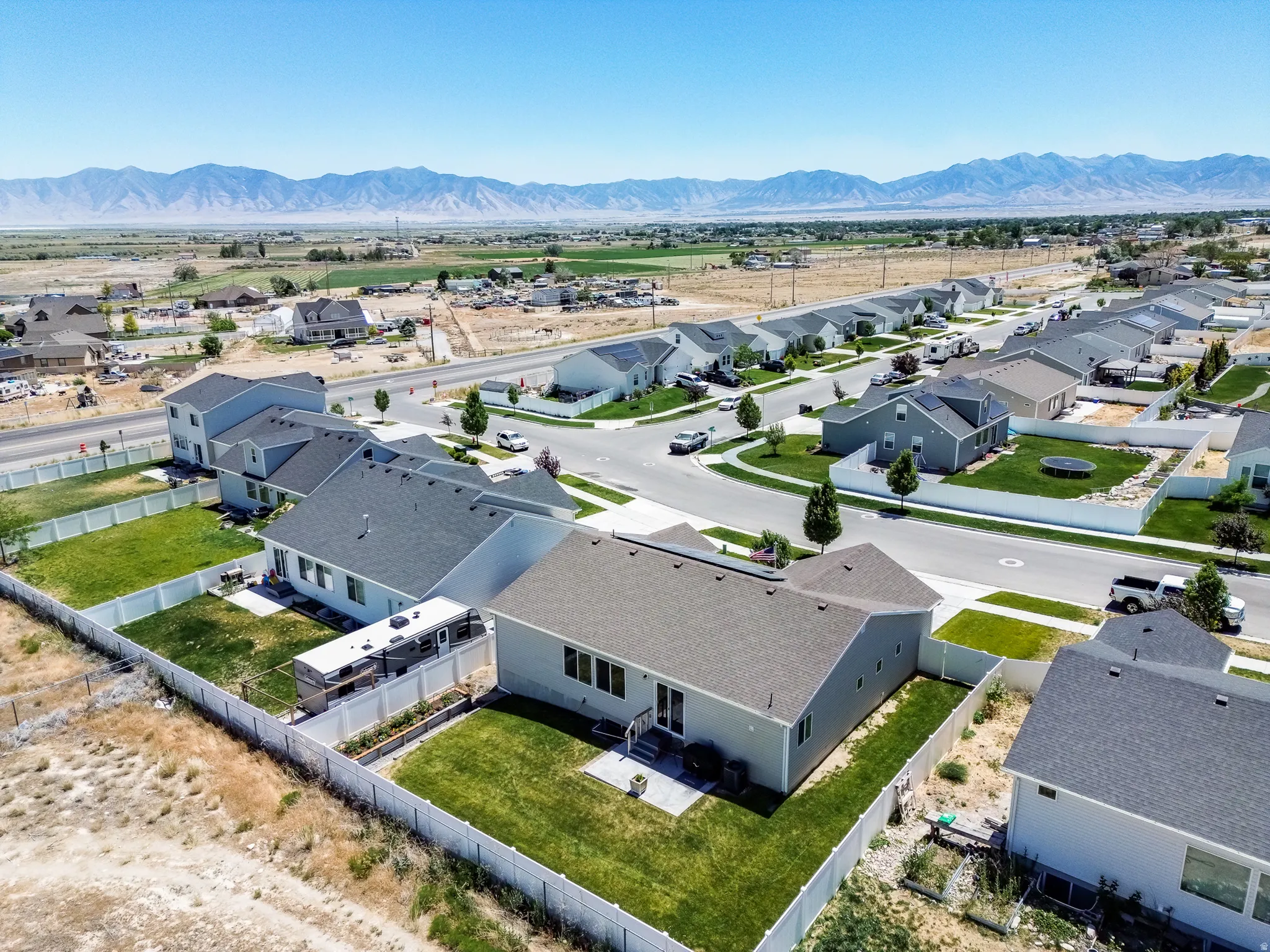 Residential neighborhood with mountain backdrop, paved streets, and fenced properties