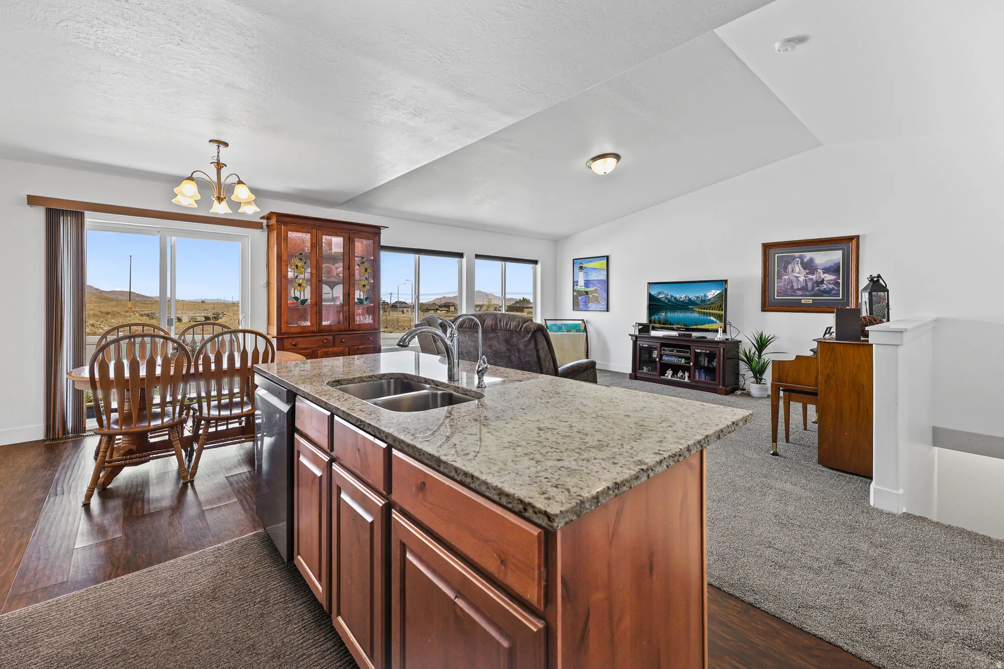 Kitchen island with granite countertop, double basin sink, and wood cabinetry