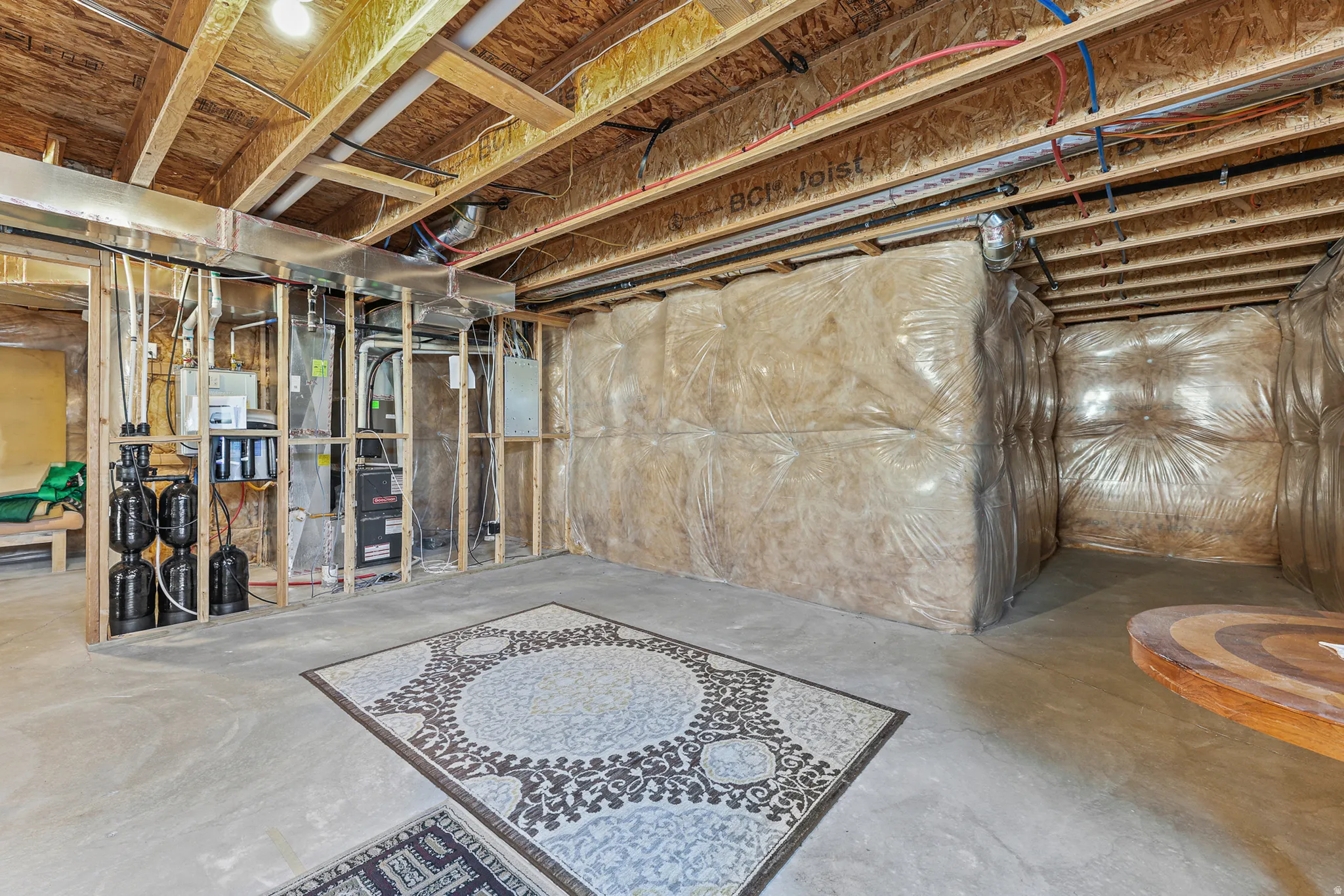Unfinished basement with exposed ceiling joists, concrete flooring, and insulated walls