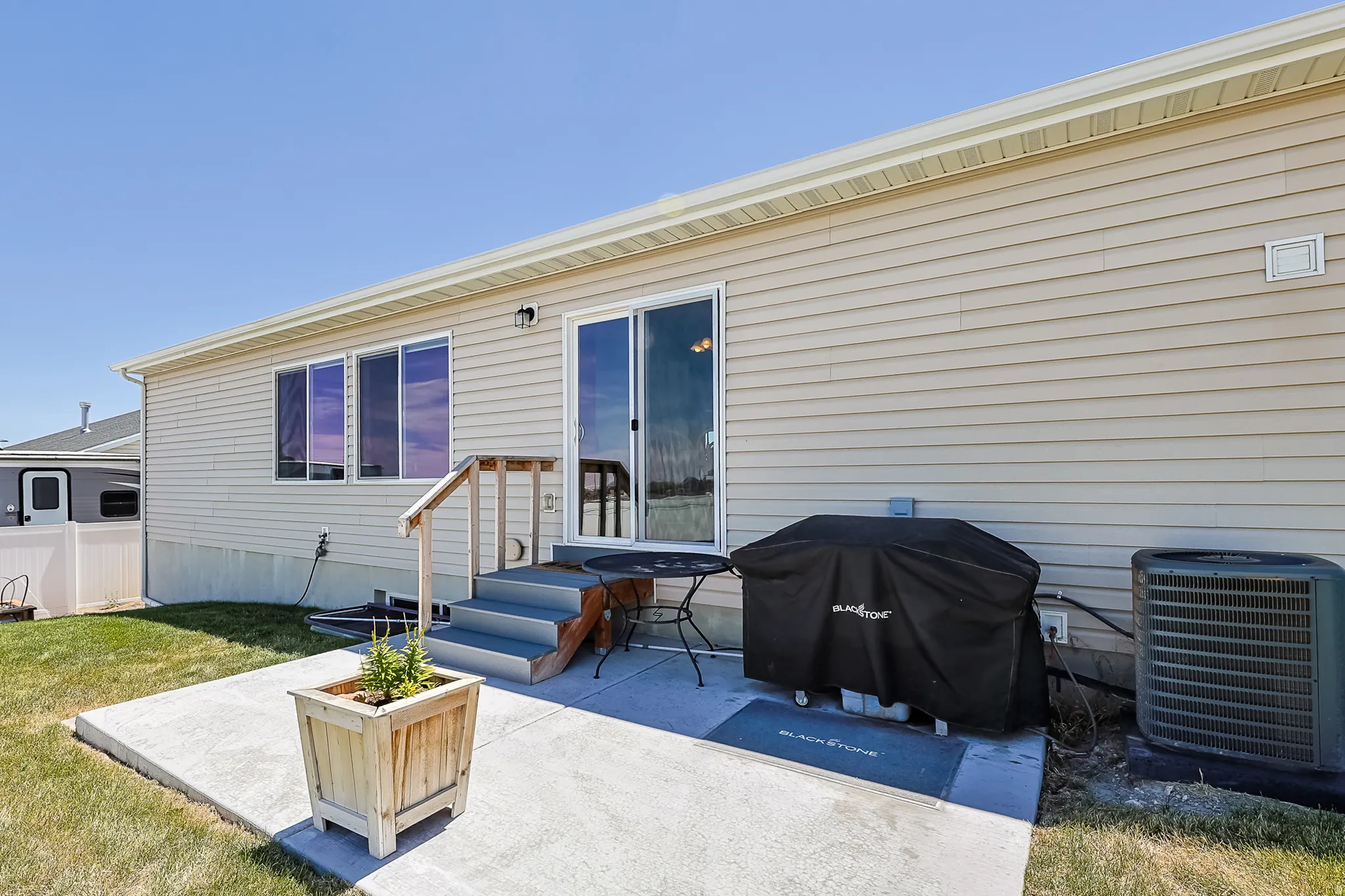 Rear exterior featuring beige siding, white trim, and a concrete patio