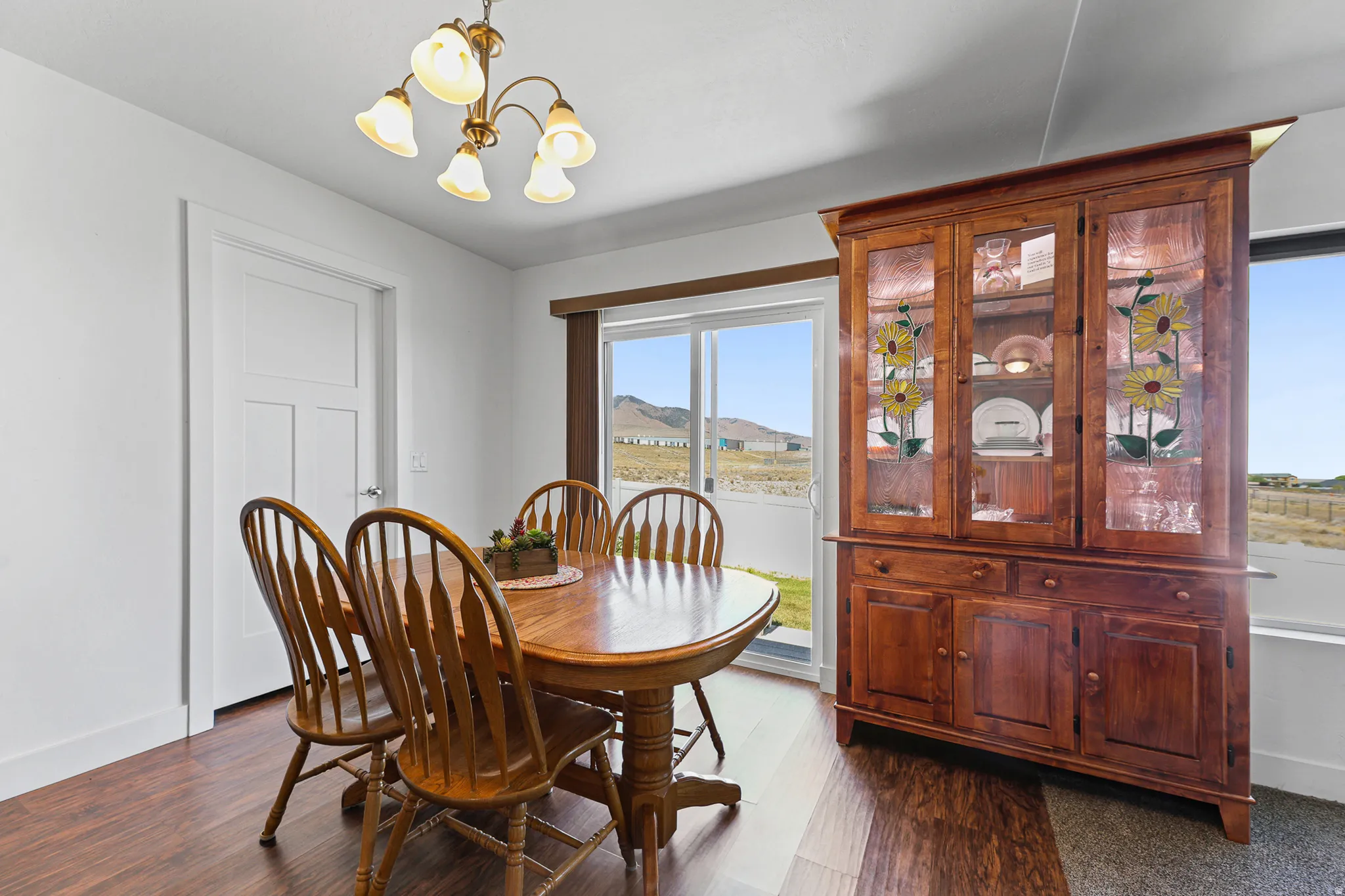 Wood-finish flooring, white paneled door, sliding glass door, and a multi-arm chandelier