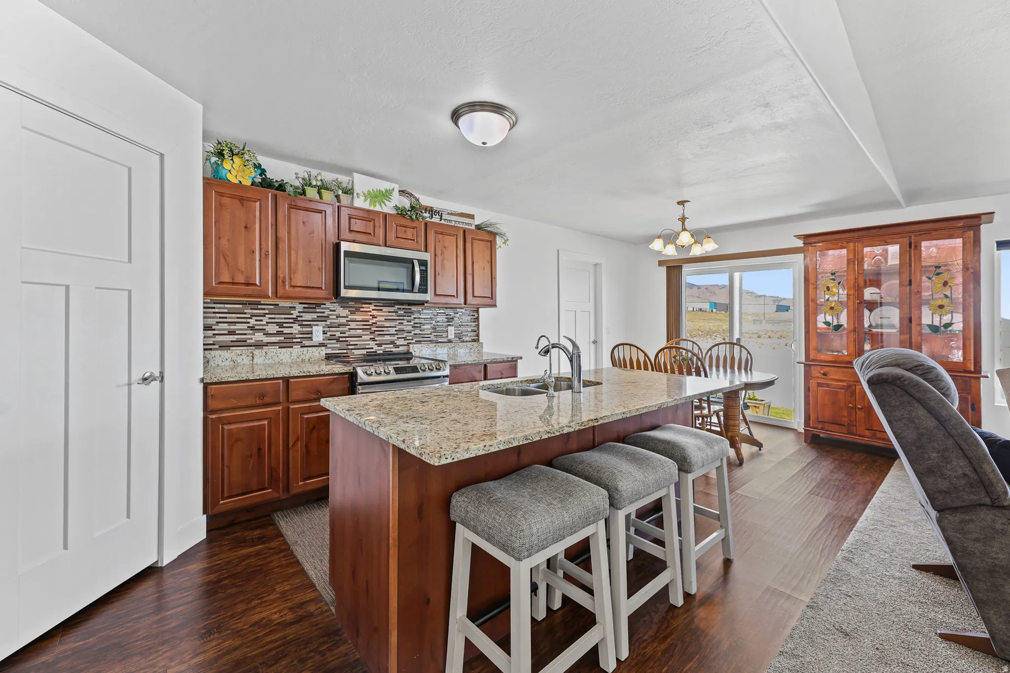 Kitchen featuring wood-finish flooring, wood cabinetry, granite countertops, and a tile backsplash