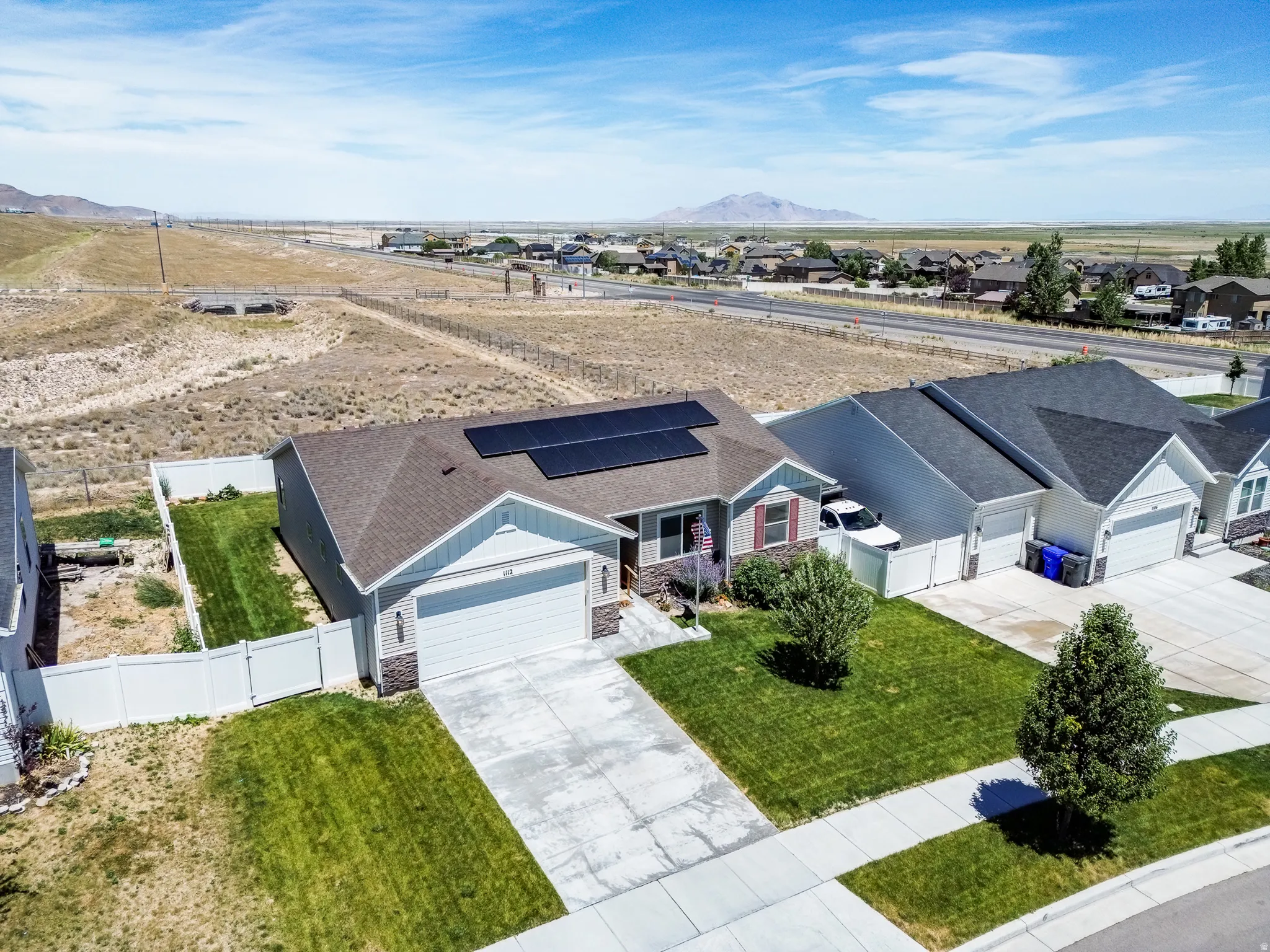Contemporary ranch-style residence featuring solar panels, a two-car garage, and a manicured front lawn