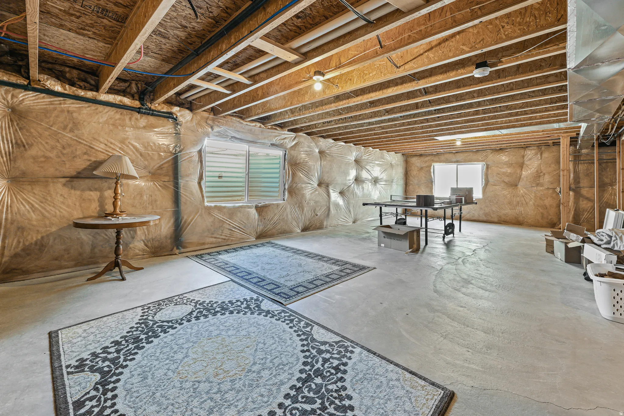 Unfinished lower level with exposed ceiling joists and concrete flooring