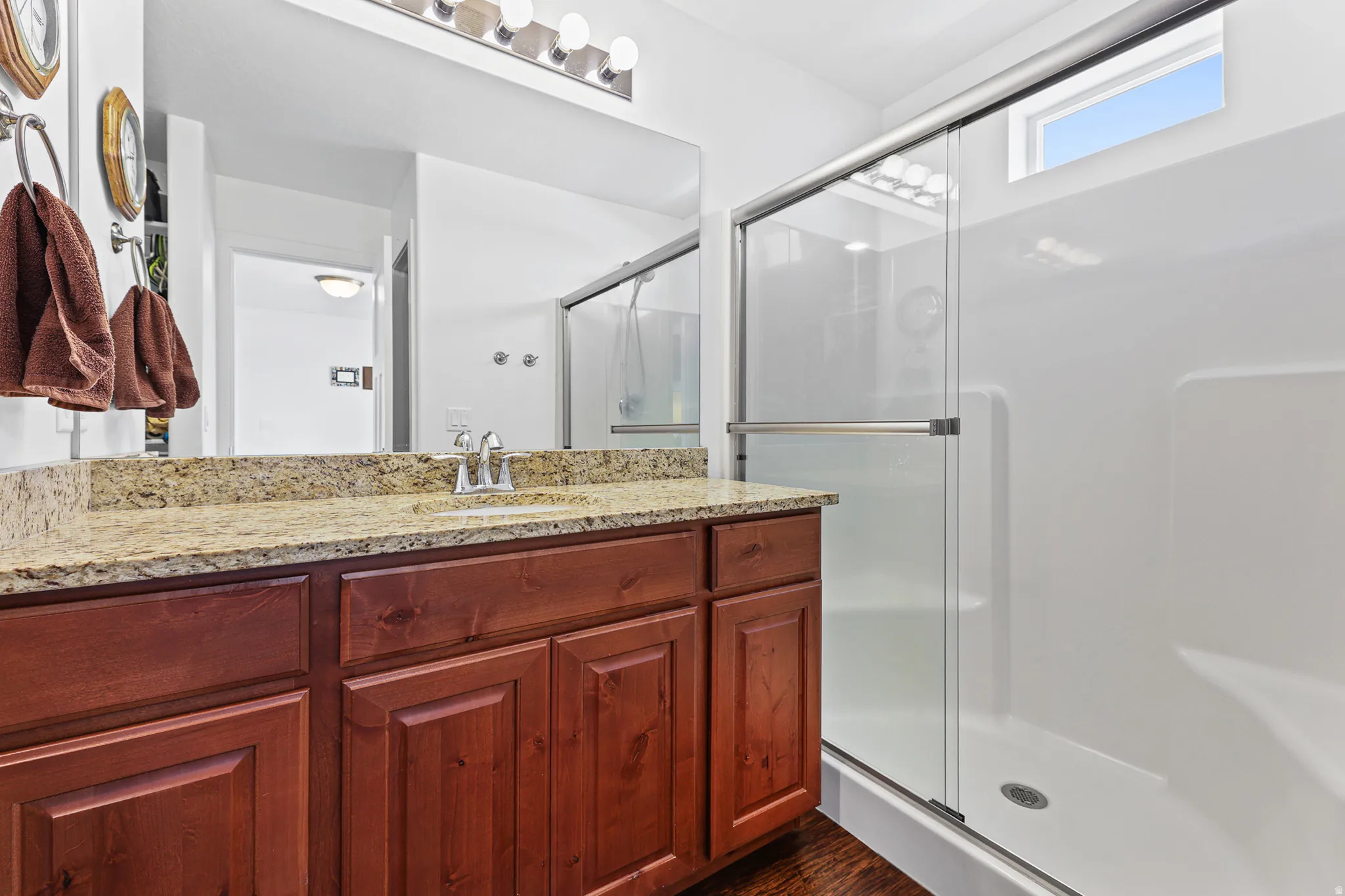 Bathroom featuring a single vanity with wood-finish cabinetry, a light-colored speckled countertop, and a chrome faucet