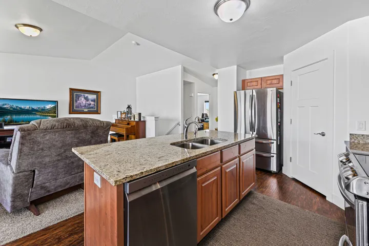 Kitchen island with a granite countertop, undermount sink, and integrated dishwasher