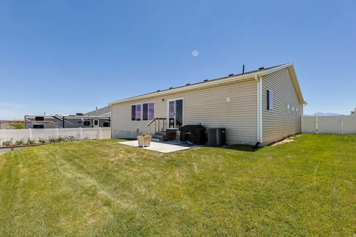 Expansive lawn area with a concrete patio, vinyl fencing, and a siding exterior