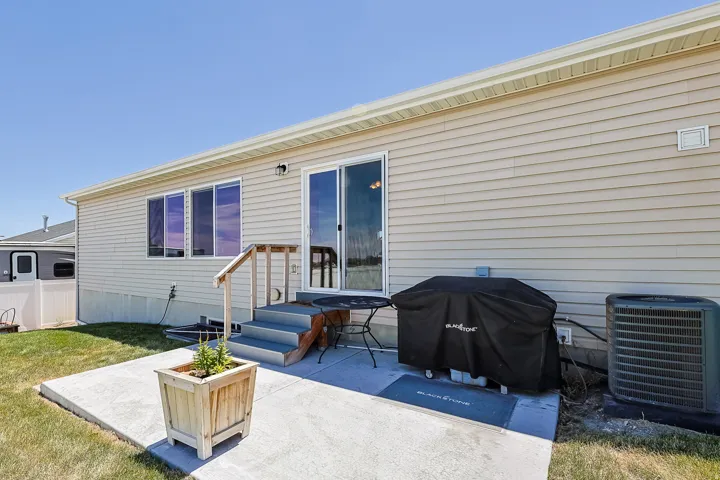 Rear exterior featuring beige siding, white trim, and a concrete patio
