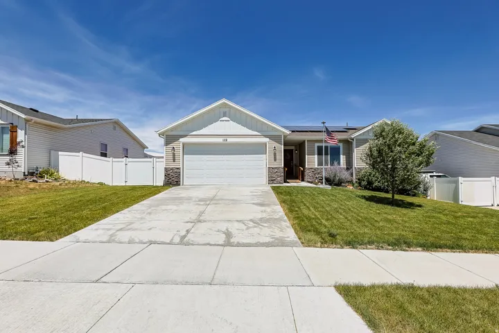Single-story residence featuring a two-car garage, stone and siding exterior, mature landscaping, and a concrete driveway