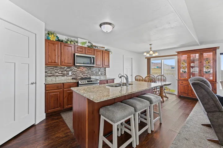Kitchen featuring wood-finish flooring, wood cabinetry, granite countertops, and a tile backsplash