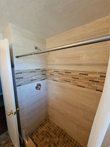 Tiled shower surround with decorative mosaic accent band and tiled floor
