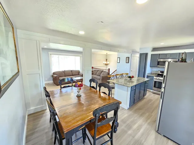 Open-concept design featuring wood-finish flooring, recessed lighting, a kitchen island with stone countertop, and stainless steel appliances