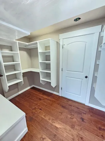 Built-in white shelving, wood-finish flooring, and a white panel door