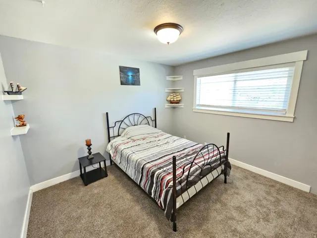 Carpeted flooring, recessed window, white window blinds, and corner floating shelves