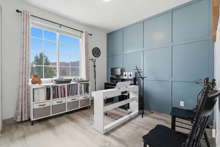 Expansive window, accent wall with paneling, wood-finish flooring, recessed lighting, and a neutral color palette
