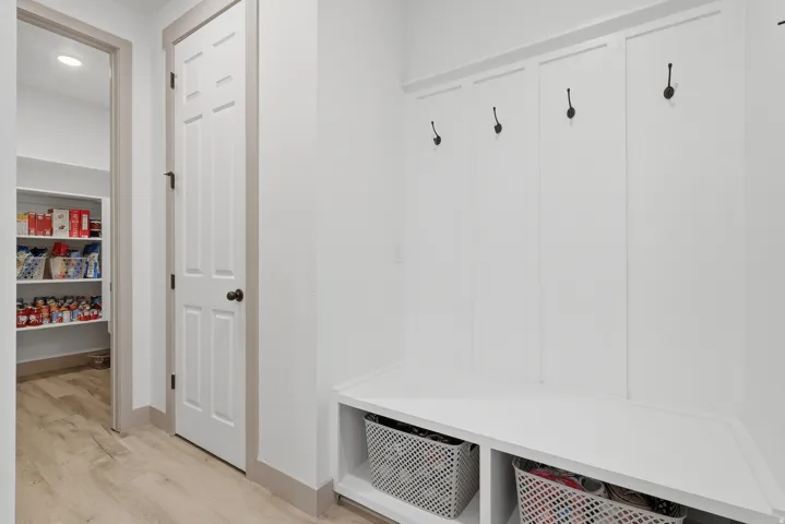 Built-in bench with open storage cubbies, wall-mounted coat hooks, and light wood-finish flooring