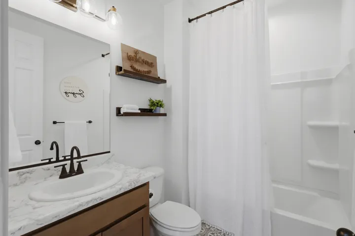 Wood-finish vanity with a single basin sink, bronze-finish faucet, and coordinating bronze-finish hardware