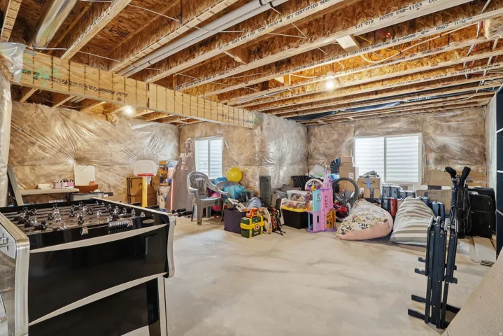 Unfinished basement featuring exposed wood joists, concrete flooring, and insulated walls