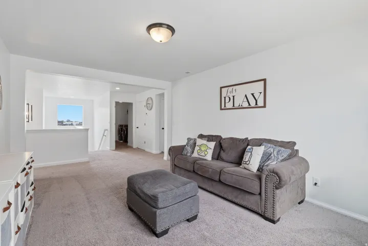 Carpeted room with a half-wall, a window, and a hallway entry