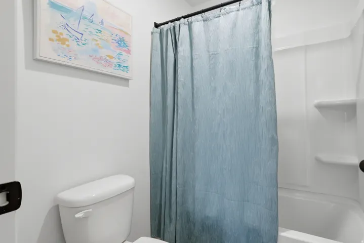 White toilet with a built-in shower/tub combination featuring integrated shelving
