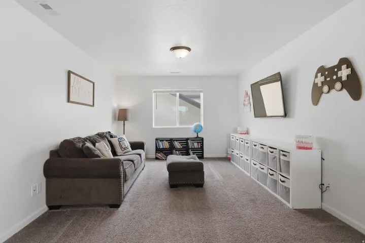 Recessed lighting illuminates a spacious room with light gray carpeting