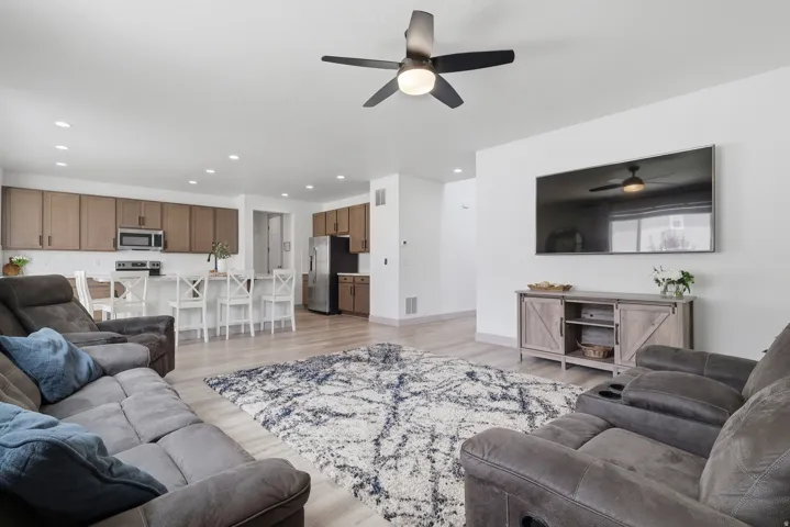 Expansive living area with wood-finish flooring, recessed lighting, and a ceiling fan