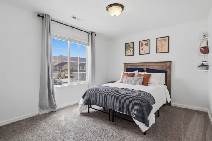 Carpeted flooring, window with mountain backdrop, wooden headboard, flush-mount ceiling light fixture, and white wall shelving