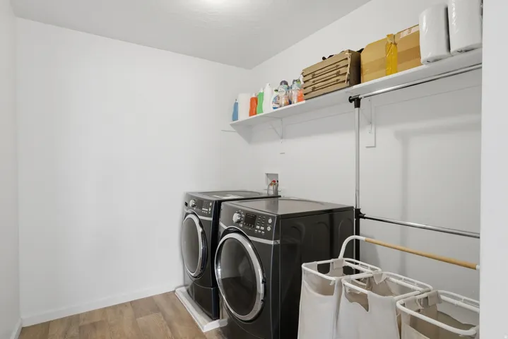 White walls, wood-finish flooring, wall-mounted shelving, and a hanging rod