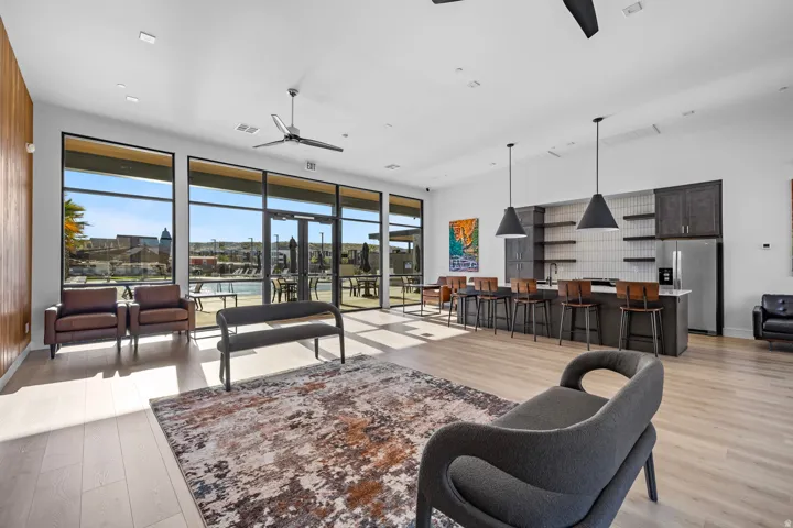 Open-concept common area featuring wood-finish flooring, a full kitchen with dark cabinetry and stainless steel appliances, and large windows with exterior access